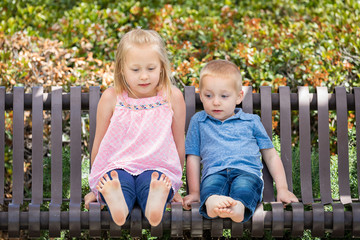 Young Sister and Brother Having Fun On The Bench At The Park