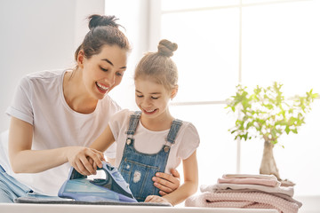 mother and daughter ironing at home