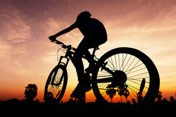 Obraz premium Ludzie jeżdżący na rowerze na wzgórzu o zmierzchu