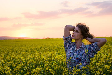 Happy young woman in a field of canola seed in bloom. Freedom, nature, ecology and happiness concept.