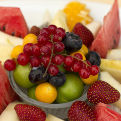 Fruits on a plate. Green plum, red currant, blueberry, strawberry, physalis, pitahaya, watermelon, orange and apple.