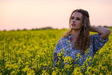 Fototapeta premium Happy young woman in a field of canola seed in bloom. Freedom, nature, ecology and happiness concept.