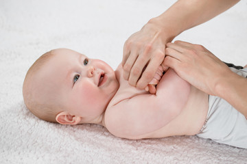 Female doctor doing massage and gymnastic baby on a light background