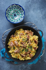 Cast-iron pan with pilaf on a blue stone background, vertical shot, above view