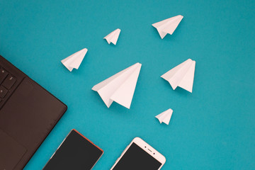 White paper planes and gadgets on a blue background. Visual communication scheme through messenger...