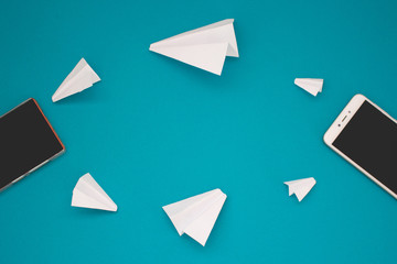 White paper planes and gadgets on a blue background. Visual communication scheme through messenger...