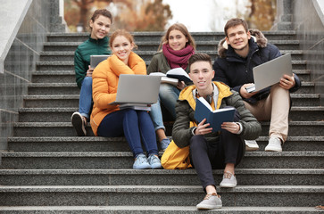Fototapeta premium Group of teenagers studying on stairs outdoors