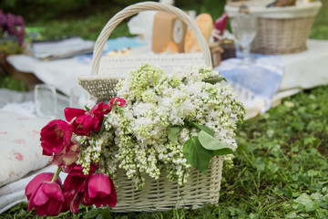 Picnic decorations, cannotier, flowers, fruits. Picnic at the park on the grass: tablecloth, basket, healthy food and accessories, top view.