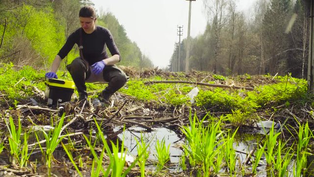 Scientist ecologist in the forest taking sample of water in the test tube
