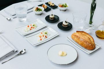 Modern French appetizer: Fresh baked loaf of bread with butter, crush and cut cheese with diced tomato and Mini white bun hamburger served with olive oil. 