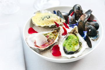 Modern French Cuisine: Oysters poached and served with lemon foam and caviar. The other smoked and served with ponzu granite. Grilled blue mussels served on white bowl that full of sea salt.