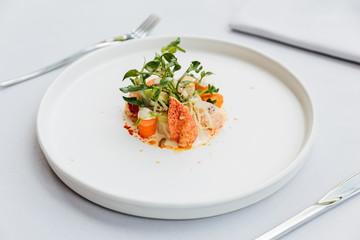 Modern French cuisine: Lobster tail salad including lobster, asparagus and roasted sunflower seeds with white sauce served in white plate.