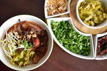 Closeup homemade northern Thai rice noodle and spicy minced park sauce or Kanom Jeen Nam Ngiaw with vegetables as side dish and copy space for text