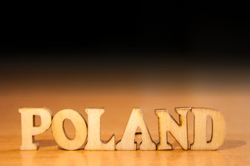 The word 'poland' made of wooden letters. wood inscription on table and dark black background
