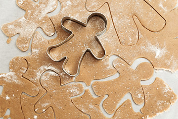 Gingerbread Cookie. New Year figures from a dough, prepared for baking in the oven. Biscuits in the form of  Gingerbread man on paper for baking. Raw biscuit cookies.