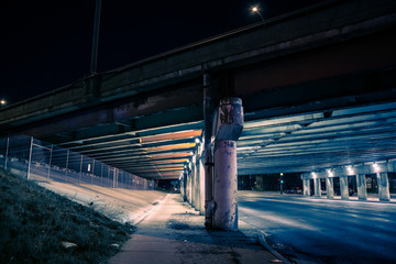 Gritty dark city highway bridge and street underpass at night