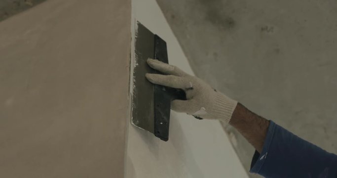 Slow motion pan of worker applying putty on the wall