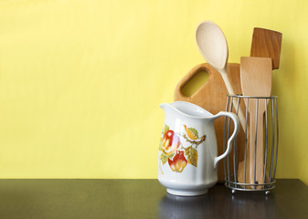 Kitchen utensils on dark shelf over yellow wall. Kitchen interior background with copy space, vertical