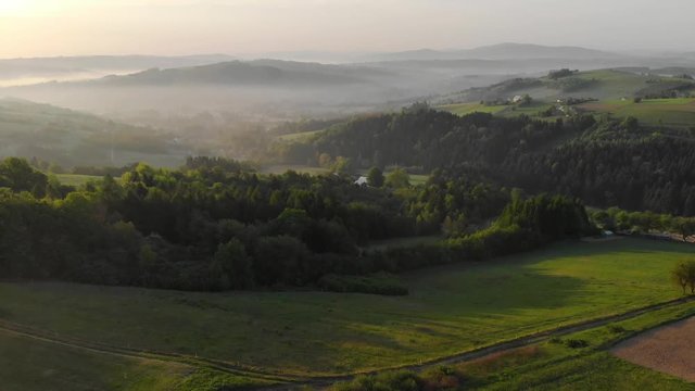 Sunrise over misty hills in Brusnik,Poland with lookout tower. Aerial fly backwards.