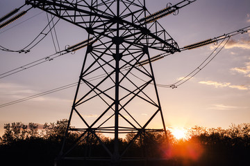 pillar of high-voltage power lines are located in the open air at sunset on the background of the evening sky