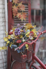 Fototapeta na wymiar A bicycle basket with old artificial flowers on a city street. Vietnam.