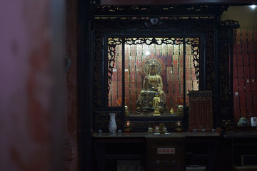 A statue of the Buddha of yellow metal in a special cupboard of a Buddhist temple