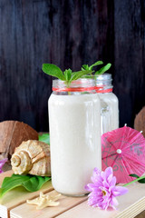 Cocktail made of coconut milk and tropical fruits in glass jars decorated with mint