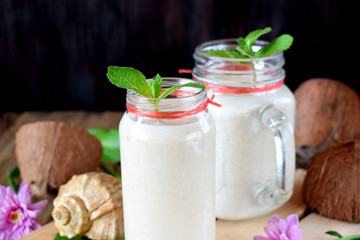 Cocktail made of coconut milk and tropical fruits in glass jars decorated with mint