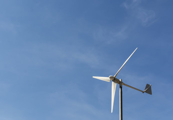 Wind turbine isolated on blue sky and clouds