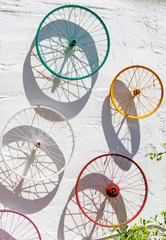 Decorated colorful bicycle wheels hung on a white wall