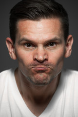 Close-up portrait of angry caucasian man on gray background