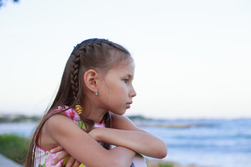 Portrait of young girl sitting on the beach looking away at the horizon in the morning