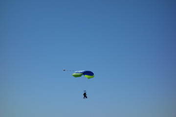 Tandem parachuting. Pair of parachutists in descent to landing