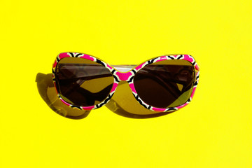 Naklejka premium Fashion Sunglasses In Colorful Frame.Studio Shot Of Colorful Sunglasses. Summer Is Coming Soon. Travel, Vacation, Summer Concept. Sunglasses On Yellow Background. Top View Of Sunglasses. 