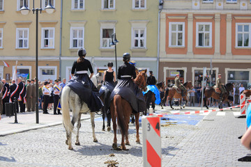 Kobiety w czarnych długich spudnicach i Żołnierze Wojska Polskiego na koniach.