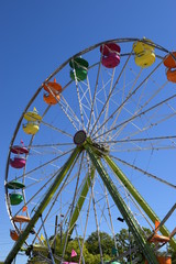 Fototapeta premium Colorful small ferris wheel against bright blue sky.