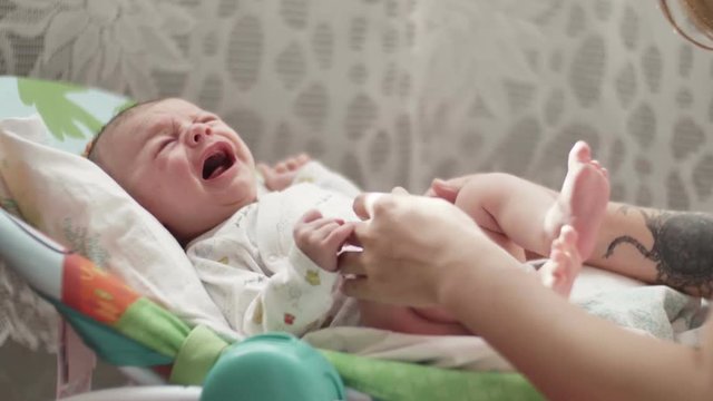 beautiful young mom kiss and soothes cry of newborn baby