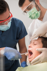 Boy with perfect teeth at the dentist doing check up with the clininc at the background - oral hygiene health care concept