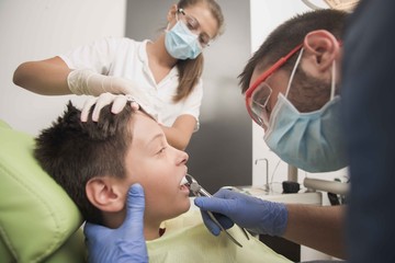 Fototapeta premium Teenager having his tooth removed at the dentist office - oral hygiene health care concept