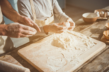 Close up of male hands adding eggs into baking powder on processing board