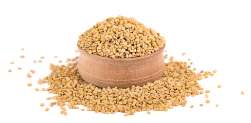 Fenugreek seeds in wooden bowl, isolated on white background