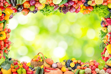 Frame of fruits and vegetables on abstract blurry plant background.