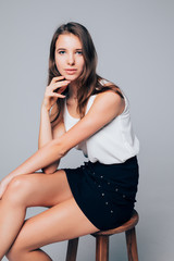Naklejka premium young female fashion model sitting on chair isolated on gray background