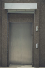 Fototapeta premium Close up grey lift metal door locating in urban building