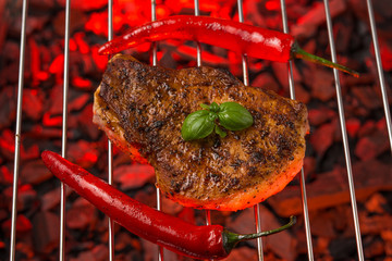 Fresh grilled steak with red chili pepper. On the corrugated grid and on burning coals.