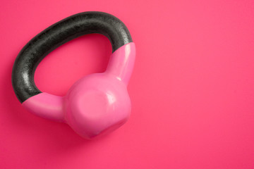 Women's kettle weights on pink background. Strong women concept.