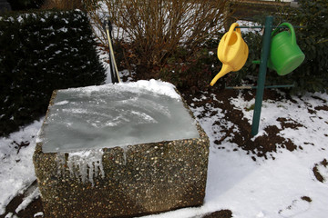 zugefrorener Wasserbottich auf dem Friedhof