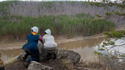 Two young caucasian females on a cliff danger looking down to river
