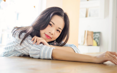 Young Chinese girl sitting in cafe, lying and looking at camera with smile face.