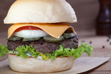 Close up of beef burger with cheese on wood table.